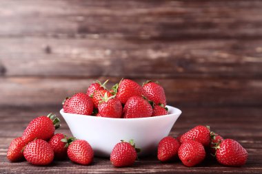 Kahverengi ahşap masada kase taze çilek