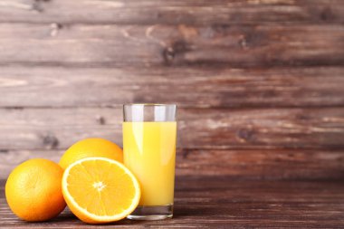 Kahverengi ahşap masa üzerinde cam portakal suyu