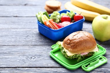 Sandviç ve sebze ahşap masa üzerinde okul öğle yemeği kutusu