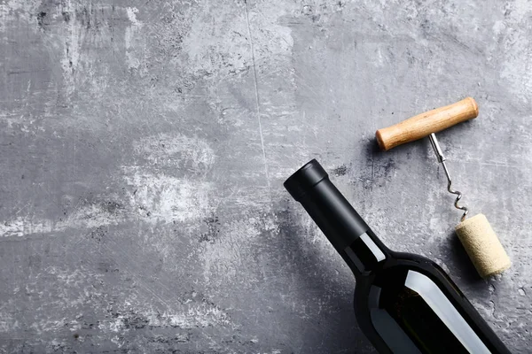 Weinflasche mit Korken und Korkenzieher auf grauem Holztisch — Stockfoto