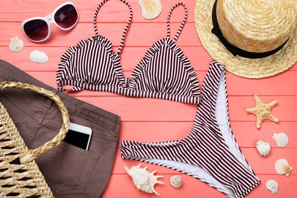 Ahşap masa üzerinde deniz kabukları ile moda mayo ve giyim