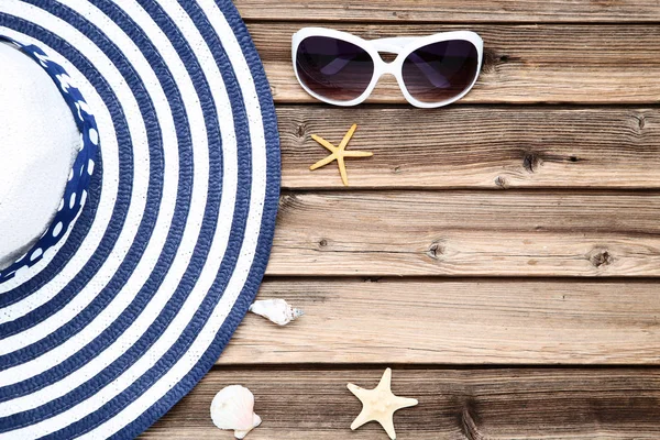 Kapelusz plażowy z muszli i okulary przeciwsłoneczne na brązowym drewnianym stole — Zdjęcie stockowe