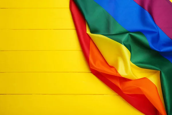 Regenboog vlag op gele houten tafel — Stockfoto