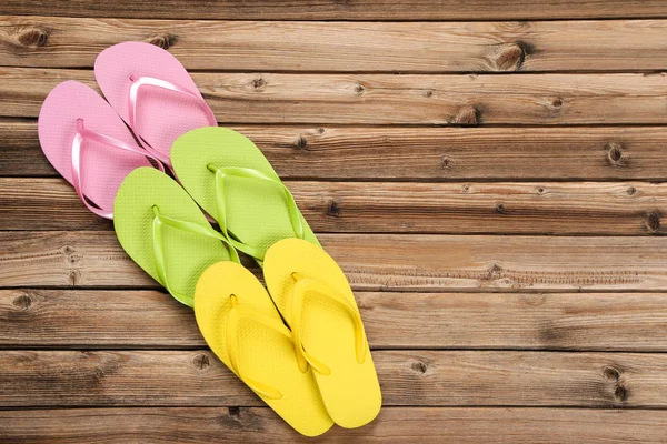 Pairs of colorful flip flops on brown wooden table — Stock Photo, Image