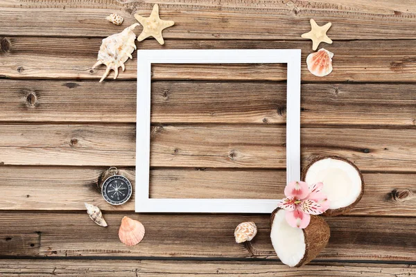 Wooden blank frame with seashells and coconuts on brown table — ストック写真