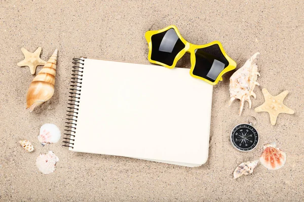 Hoja de papel en blanco con conchas marinas y gafas de sol sobre arena de playa — Foto de Stock