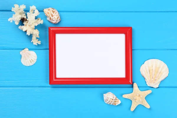 Wooden blank frame with seashells on blue table — ストック写真