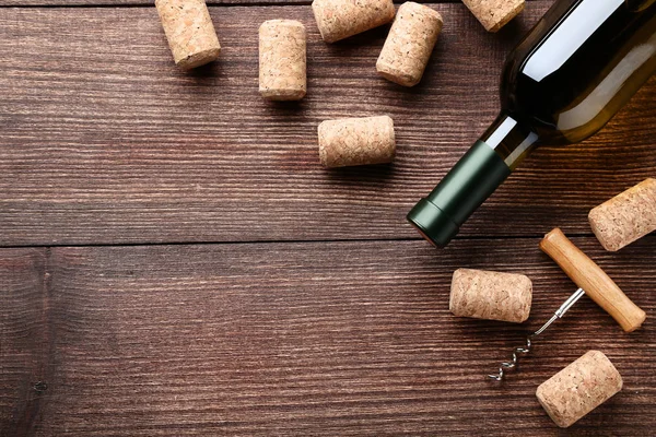Láhev na víno zátky a vývrtka na hnědý dřevěný stůl — Stock fotografie