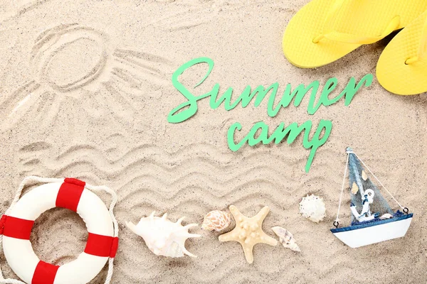 Texto en papel Campamento de verano con conchas marinas y boya salvavidas en arena de playa — Foto de Stock