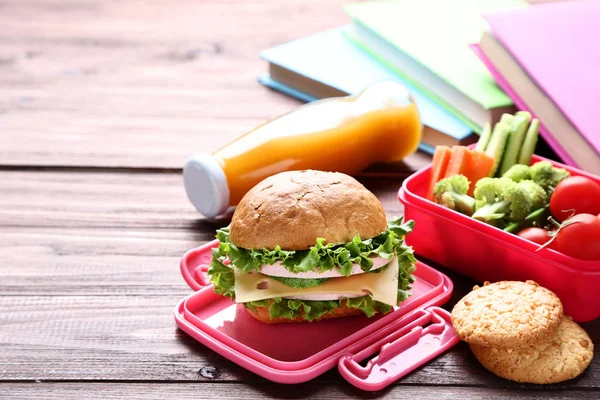 School lunch box with sandwich and bottle of juice on wooden tab — Stock Photo, Image