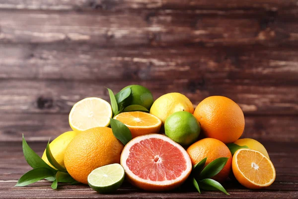 Citrusvruchten met groene blaadjes op bruine houten tafel — Stockfoto