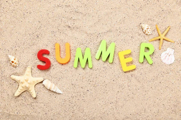 Palabra de verano con conchas marinas en arena de playa — Foto de Stock