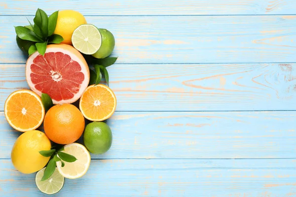 Citrus fruits with green leafs on blue wooden table — Stock Photo, Image