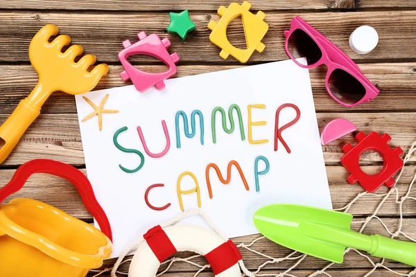 Text-Sommerlager mit Sonnenbrille und Plastikspielzeug auf braunem Holz — Stockfoto