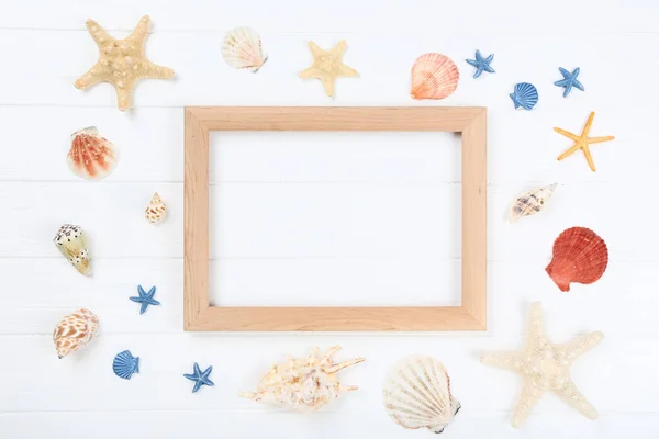 Wooden blank frame with seashells on white table — Stock Photo, Image