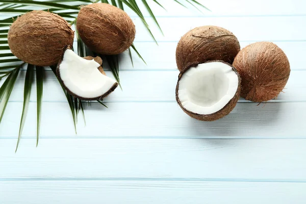 Rijpe kokosnoten met Palm blaadjes op witte houten tafel — Stockfoto