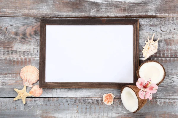 Wooden blank frame with seashells and coconuts on brown table — ストック写真