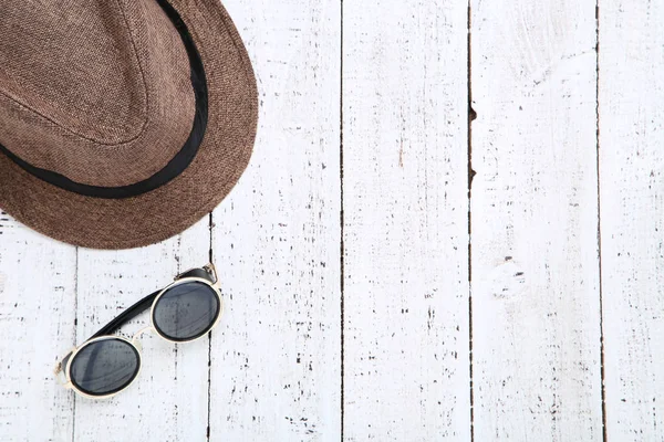 Коричнева шапка з сонцезахисних окулярів на білому дерев'яному столі — стокове фото