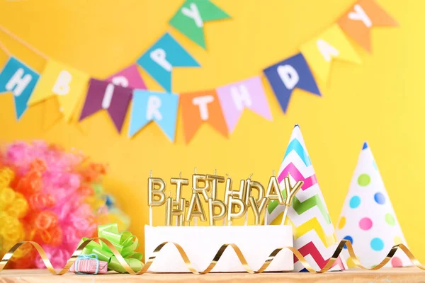 Velas de aniversário feliz com decorações de festa no backgrou amarelo — Fotografia de Stock