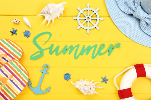 Wort Sommer mit Muscheln und Kleidung auf gelbem Holztisch — Stockfoto