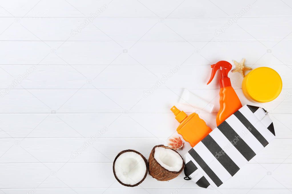 Sunscreen bottles with coconuts and seashells on white wooden ta