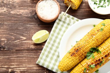 Ahşap masada limon parçası, maydanoz ve tuz ile ızgara mısır