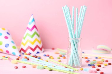 Pembe arka planda şekerler ile cam kavanoz kağıt pipo