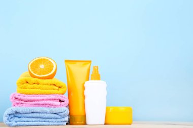 Mavi ba turuncu meyve ve güneş kremi şişeleri ile katlanmış havlu