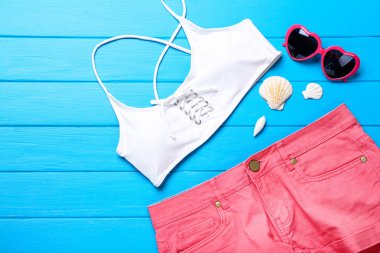 Mavi ahşap ta üzerinde deniz kabukları ve güneş gözlüğü ile Moda giyim