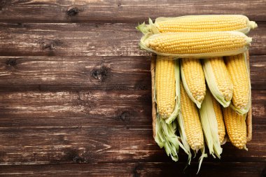 Kahverengi ahşap masada olgun mısır.