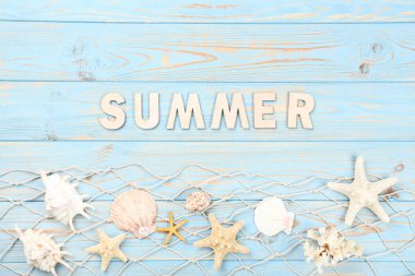 Söz Yazı deniz kabukları ve mavi ahşap masada balık ağıyla