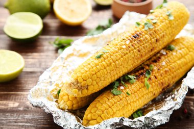 Kahverengi ahşap masa üzerinde yeşil maydanoz Leafs ile ızgara Mısır