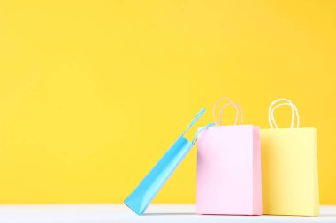 Sarı arka plan üzerinde küçük kağıt alışveriş çantaları