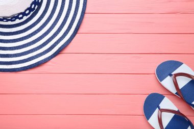 Ahşap masa üzerinde parmak arası terlikli plaj şapkası