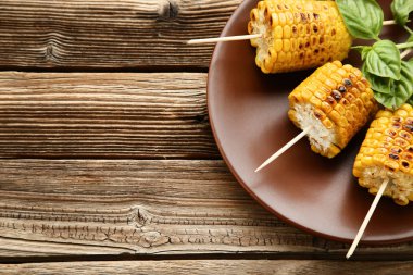 Ahşap masa üzerinde yeşil fesleğen yaprakları ile ızgara mısır