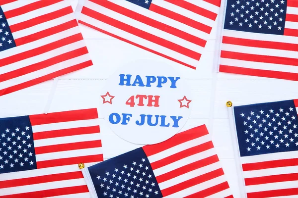 Tekst gelukkig 4 juli met Amerikaanse vlaggen op witte houten tafel — Stockfoto