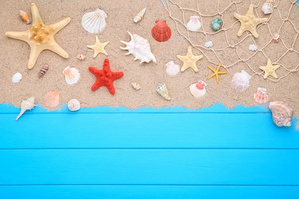 Seashells com areia de praia em mesa de madeira azul — Fotografia de Stock