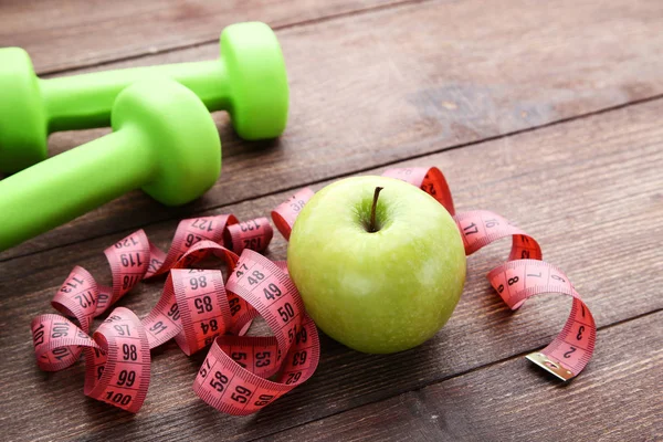 Halter ve kahverengi ahşap masa üzerinde elma ile ölçüm bandı