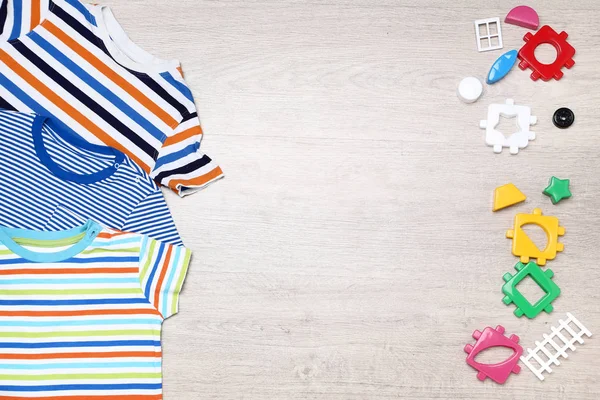 Baju bayi dengan mainan plastik di lantai — Stok Foto