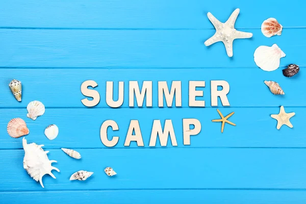 Text letní tábor s mušlí na modrém dřevěném stole — Stock fotografie