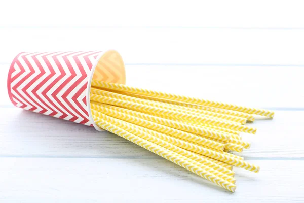 Yellow paper straws in cup on wooden table — Stock Photo, Image