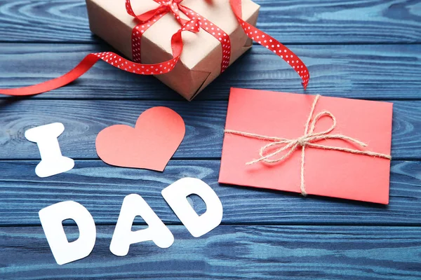 Text I Love Dad with envelope and gift box on wooden table
