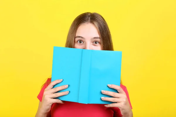 Молода дівчина з книгою на жовтому фоні — стокове фото