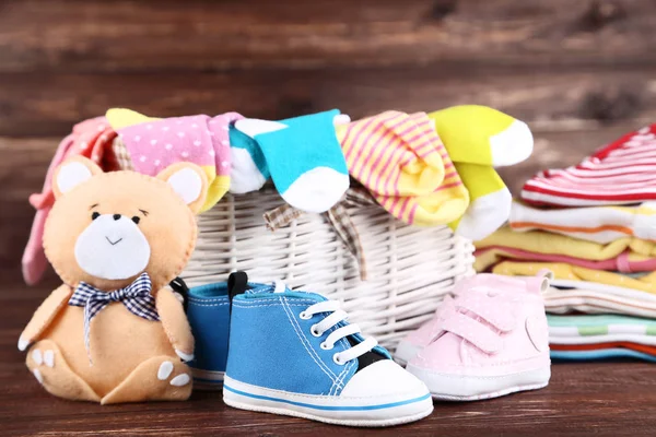 Roupas de bebê dobradas com brinquedo de urso macio na mesa de madeira marrom — Fotografia de Stock