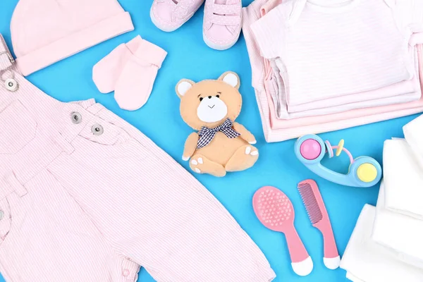 Bayi pakaian dengan mainan dan sikat rambut pada latar belakang biru — Stok Foto