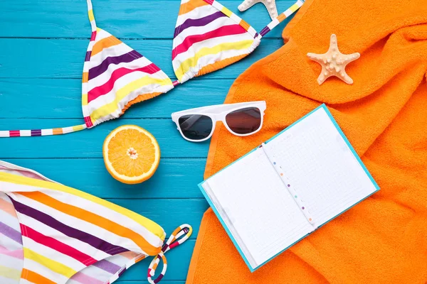 Mavi ahşap masa üzerinde denizyıldızı ve not defteri ile Moda mayo