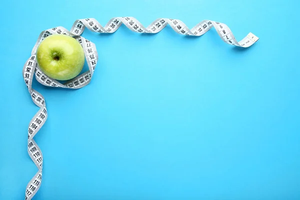 Fita de medição com maçã doce no fundo azul — Fotografia de Stock