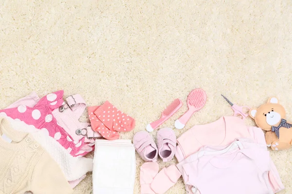 Pakaian dengan mainan dan perlengkapan bayi di karpet — Stok Foto
