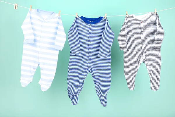 Roupas de bebê penduradas no fundo azul — Fotografia de Stock