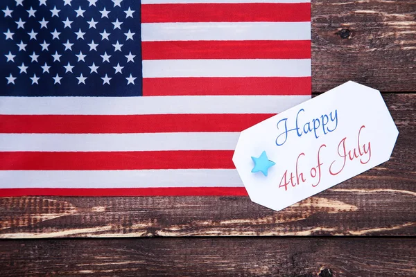 Text Happy 4 juli med amerikanska flaggan på brunt träbord — Stockfoto